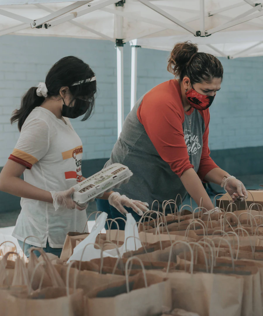 Volunteers packing paper bags of food