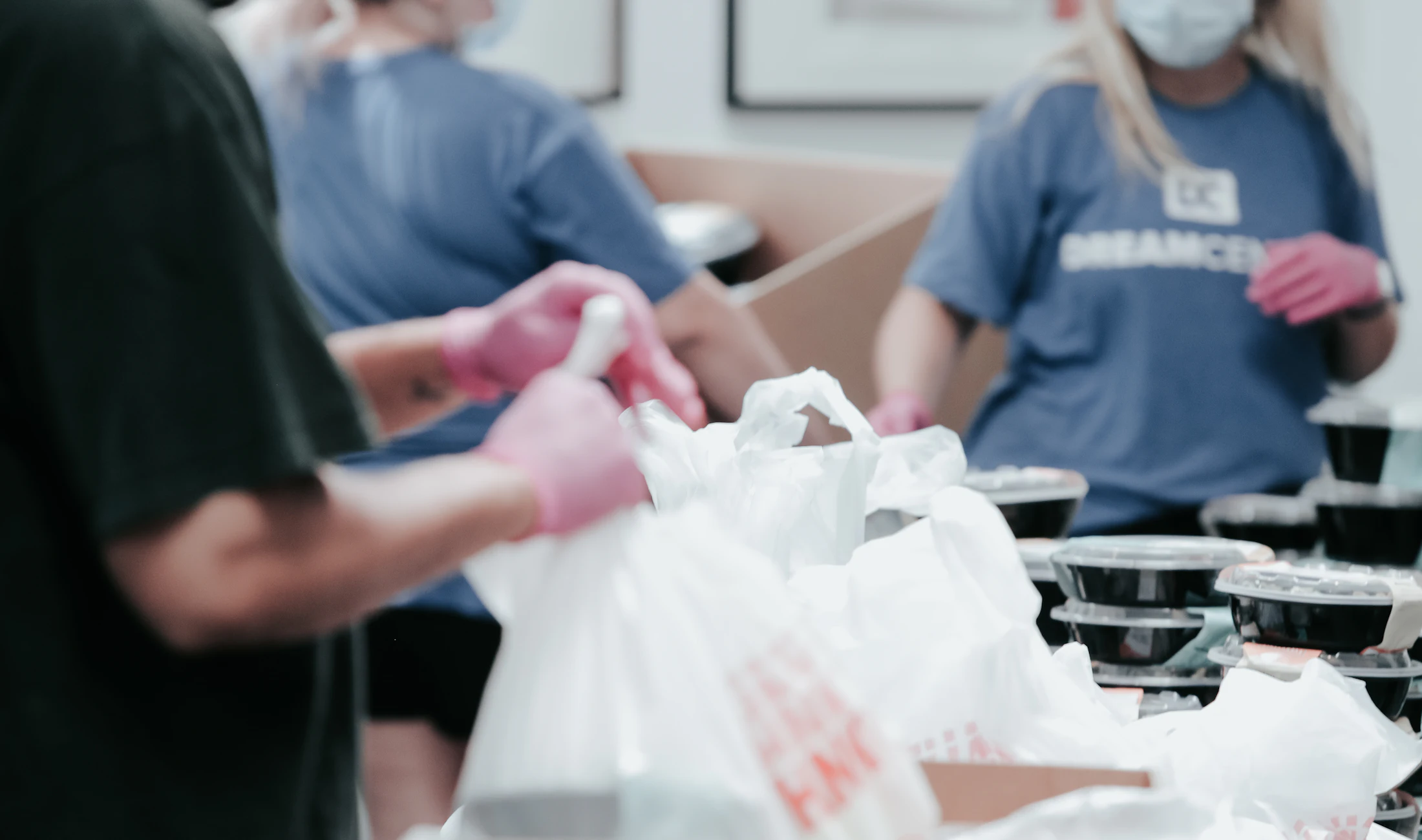 Volunteers in gloves packing groceries into bags